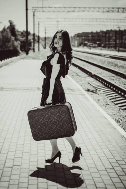 Eski sinema tarzı. Platformda bavulu olan yeşil kadife elbiseli güzel bir kızıl kadın.