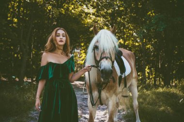 Peri masalı ormanında at süren mistik bir kadın. At ve insan kavramı. Klasik stil sanatsal kadın portresi. Sonbaharda at ile dışarıda yürüyor.