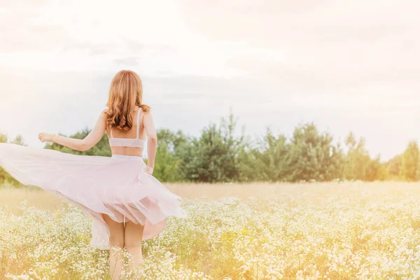 Flowers and romantic woman in the field. Lit evening sun, Beauty Romantic Girl Outdoors. Blowing Long Hair. Glow Sun, Sunshine. Toned in warm colors