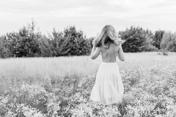 Flowers and romantic woman in the field. Lit evening sun, Beauty Romantic Girl Outdoors. Blowing Long Hair. Glow Sun, Sunshine. Toned in warm colors