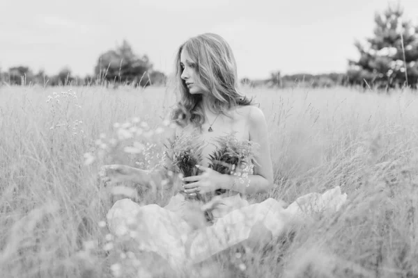 Flowers and romantic woman in the field. Lit evening sun, Beauty Romantic Girl Outdoors. Blowing Long Hair. Glow Sun, Sunshine. Toned in warm colors