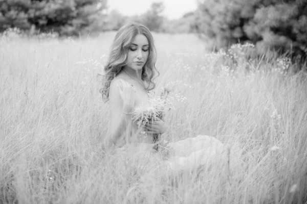 Flowers and romantic woman in the field. Lit evening sun, Beauty Romantic Girl Outdoors. Blowing Long Hair. Glow Sun, Sunshine. Toned in warm colors