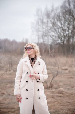 Beyaz kürklü kadın ceketi, leopar atkısı, kedi gözü gözlükleri, sarışın hoş bayan portresi, moda konsept.