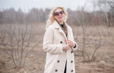 Beyaz kürklü kadın ceketi, leopar atkısı, kedi gözü gözlükleri, sarışın hoş bayan portresi, moda konsept.