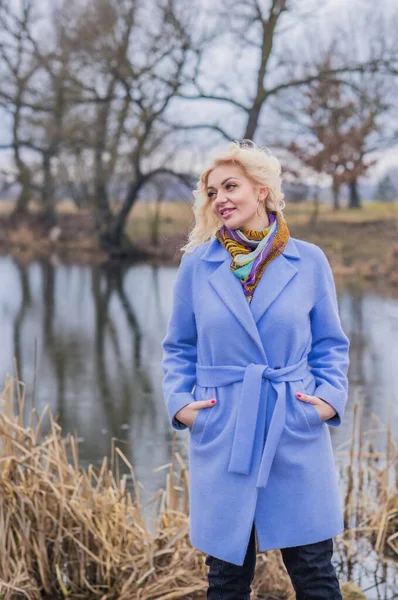 Woman in violet coat, colorful scarf, portrait of blonde nice lady at city park, trendy concept