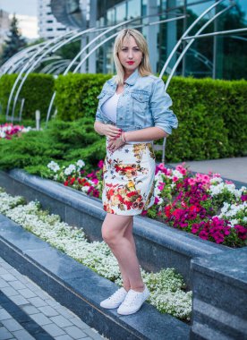 Şık giyinen genç sarışın kadın şehir sokaklarında yürüyor, şık bir bayan, moda. Artı sokaktaki boy modeli.