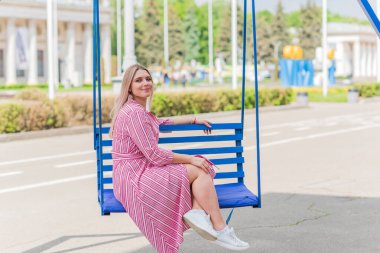 Büyük bedenli, Amerikan ya da Avrupa görünümlü mutlu bir kadın şehirde hayatın tadını çıkarıyor. Aşırı kilolu genç bir bayan, şehir parkında şık giyinmiş. Doğal güzellik.