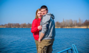 Artı parkta yürüyen çift bedenli aşıklar. Genç bir adam ve şişman bir çift tatilde.