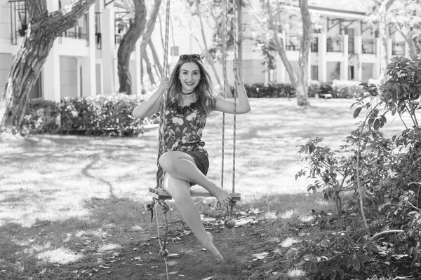 Happy moments of life. Vacation concept. Happy young woman at good mood sitting on swing enjoying garden view.