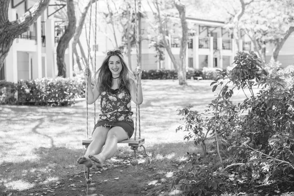 Happy moments of life. Vacation concept. Happy young woman at good mood sitting on swing enjoying garden view.