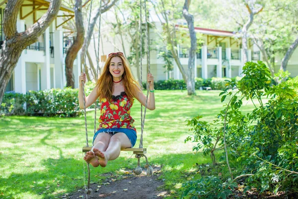 Happy moments of life. Vacation concept. Happy young woman at good mood sitting on swing enjoying garden view.