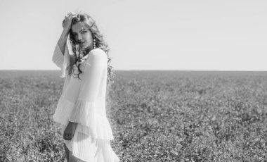 Özgürlük kavramı. Yeşil tarlada genç, mutlu bir kadın, akşam ışığı. Arkadaki mavi gökyüzü. Güzel kız doğanın tadını çıkarıyor. Beyaz elbiseli güzel bir genç kız çayırda koşuyor.