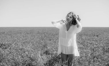 Özgürlük kavramı. Yeşil tarlada genç, mutlu bir kadın, akşam ışığı. Arkadaki mavi gökyüzü. Güzel kız doğanın tadını çıkarıyor. Beyaz elbiseli güzel bir genç kız çayırda koşuyor.