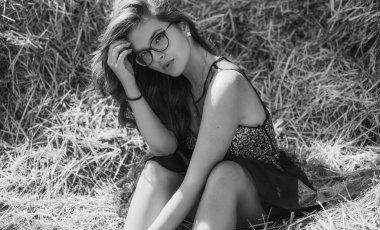 Siyah tül elbiseli ve gözlüklü seksi Asyalı kadın mısır gevreği tarlasında rüya görüyor. Güzel romantik kız saman yığınına karşı. Samanlıklarla dolu bir tarlada tatlı bir kızın fotoğrafı.