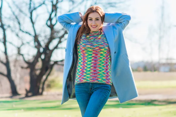 Nice smiling redhead woman with good mood at spring day, casual style, girl wearing wool blue coat and colorful sweater