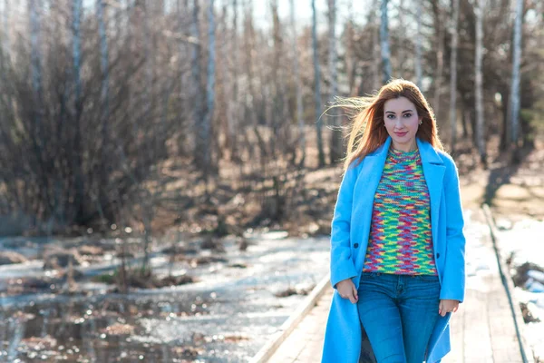 Nice smiling redhead woman with good mood at spring day, casual style, girl wearing wool blue coat and colorful sweater