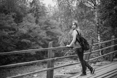 Sonbahar, doğa ve insan kavramı. Sırt çantalı güzel bir kadın sonbahar parkında dinleniyor. Oldukça iyi bir kadın gezgin rahatlar. Dağları sevmek, konsept macera açık havada aktif tatiller