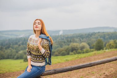 Sonbahar, doğa ve insan kavramı. Sırt çantalı güzel bir kadın sonbahar parkında dinleniyor. Oldukça iyi bir kadın gezgin rahatlar. Dağları sevmek, konsept macera açık havada aktif tatiller