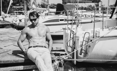 Yelkenlideki yakışıklı adam, lüks deniz yolculuğunda rahatlama, yaz tatilinde su taşımacılığı, özgürlük ve keyif konsepti.