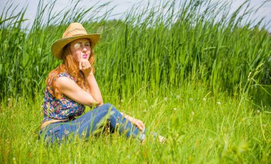 Sazlıkta gülümseyen saman şapkalı olumlu bir genç kadın, klasik tarzda, nehir veya gölde dinleniyor. Amerikan tarzı