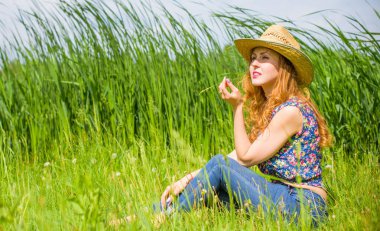 Sazlıkta gülümseyen saman şapkalı olumlu bir genç kadın, klasik tarzda, nehir veya gölde dinleniyor. Amerikan tarzı