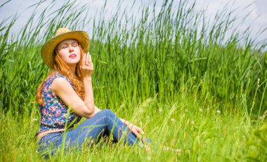 Sazlıkta gülümseyen saman şapkalı olumlu bir genç kadın, klasik tarzda, nehir veya gölde dinleniyor. Amerikan tarzı