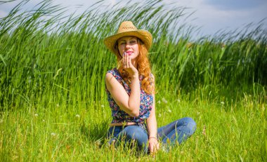 Sazlıkta gülümseyen saman şapkalı olumlu bir genç kadın, klasik tarzda, nehir veya gölde dinleniyor. Amerikan tarzı