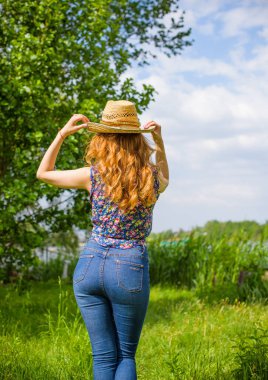 Sazlıkta gülümseyen saman şapkalı olumlu bir genç kadın, klasik tarzda, nehir veya gölde dinleniyor. Amerikan tarzı