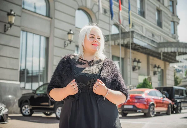 Woman of plus size, American or European appearance walks at the city enjoying life. A young lady with excess weight, xl size at the center of the city. Natural beauty