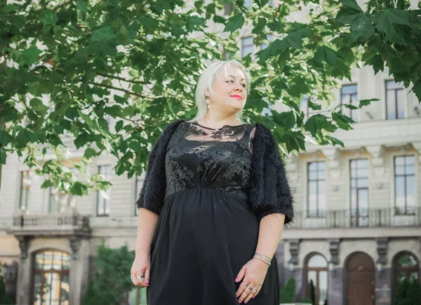 Woman of plus size, American or European appearance walks at the city enjoying life. A young lady with excess weight, xl size at the center of the city. Natural beauty