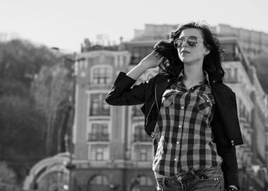 Güzel ve şık esmer kadın güneşli bir günde şehirde yürüyor, modern gündelik tarzda.