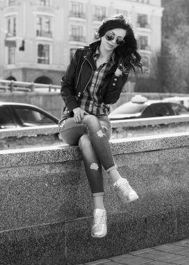 Güzel ve şık esmer kadın güneşli bir günde şehirde yürüyor, modern gündelik tarzda.