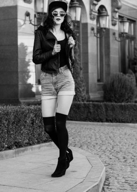 Güzel ve şık esmer kadın güneşli bir günde şehirde yürüyor, modern gündelik tarzda.