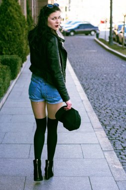 Güzel ve şık esmer kadın güneşli bir günde şehirde yürüyor, modern gündelik tarzda.