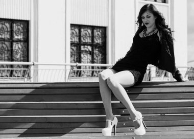 Güzel ve şık esmer kadın güneşli bir günde şehirde yürüyor, modern gündelik tarzda.