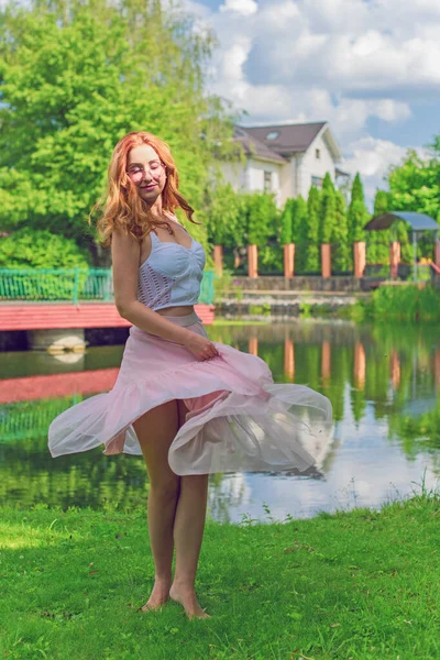 Free relaxed Woman Enjoying Nature. Beauty Girl Outdoor. Freedom concept. Beauty lady with red hair over Sky and Son. Enjoying at the meadow