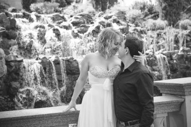 Bahçede çiçeklerin arasında, uzun, açık renk bir elbiseyle muhteşem şekilleri olan güzel sarışın gelin. Gelin ve damat yolda.