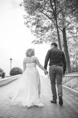 Bahçede çiçeklerin arasında, uzun, açık renk bir elbiseyle muhteşem şekilleri olan güzel sarışın gelin. Gelin ve damat yolda.