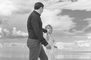 Bahçede çiçeklerin arasında, uzun, açık renk bir elbiseyle muhteşem şekilleri olan güzel sarışın gelin. Gelin ve damat yolda.