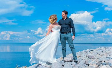 Bahçede çiçeklerin arasında, uzun, açık renk bir elbiseyle muhteşem şekilleri olan güzel sarışın gelin. Gelin ve damat yolda.