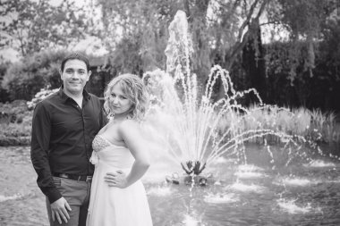 Bahçede çiçeklerin arasında, uzun, açık renk bir elbiseyle muhteşem şekilleri olan güzel sarışın gelin. Gelin ve damat yolda.