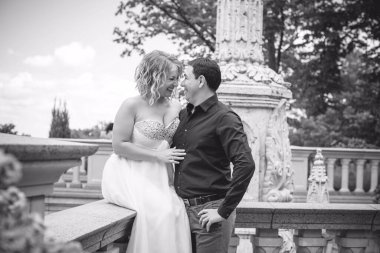 Bahçede çiçeklerin arasında, uzun, açık renk bir elbiseyle muhteşem şekilleri olan güzel sarışın gelin. Gelin ve damat yolda.