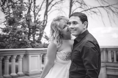 Bahçede çiçeklerin arasında, uzun, açık renk bir elbiseyle muhteşem şekilleri olan güzel sarışın gelin. Gelin ve damat yolda.