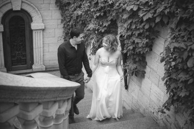 Bahçede çiçeklerin arasında, uzun, açık renk bir elbiseyle muhteşem şekilleri olan güzel sarışın gelin. Gelin ve damat yolda.