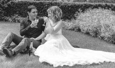 Bahçede çiçeklerin arasında, uzun, açık renk bir elbiseyle muhteşem şekilleri olan güzel sarışın gelin. Gelin ve damat yolda.