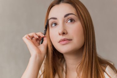 Sıradan bir kız, evde makyaj yapıyor. Telafi süreci, adım adım. Göz ve yüz makyajı.