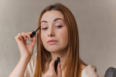 Sıradan bir kız, evde makyaj yapıyor. Telafi süreci, adım adım. Göz ve yüz makyajı.