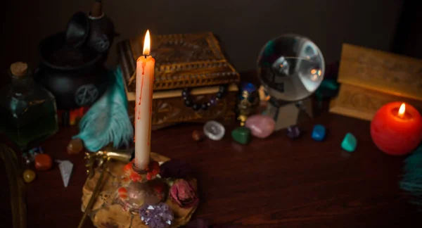 A fortune teller, witch stuff on a table, candles and fortune-telling objects. The concept of divination, astrology and esotericism