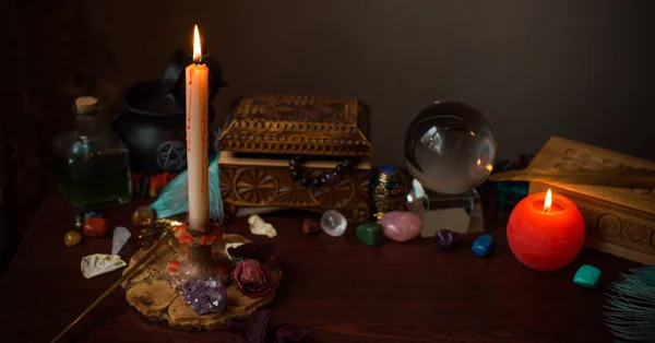 A fortune teller, witch stuff on a table, candles and fortune-telling objects. The concept of divination, astrology and esotericism