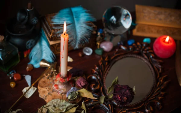 A fortune teller, witch stuff on a table, candles and fortune-telling objects. The concept of divination, astrology and esotericism